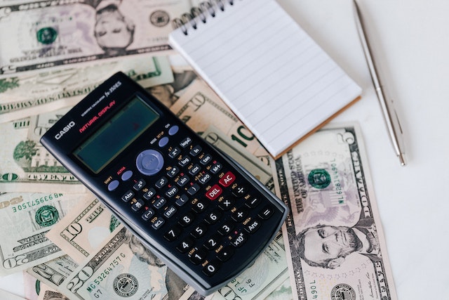 calculate and notepad on top of dollar bills